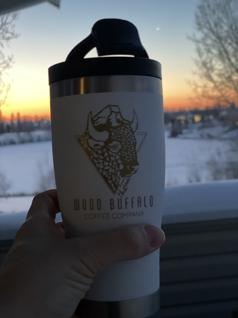 snow white 16 oz adventure tumbler with gold wood buffalo coffee logo buffalo head in front of winter sunrise